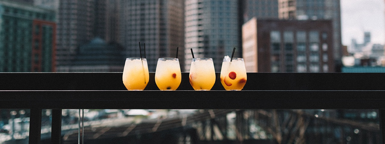 Cocktails on a leaner at a rooftop bar with high rise buildings in the background