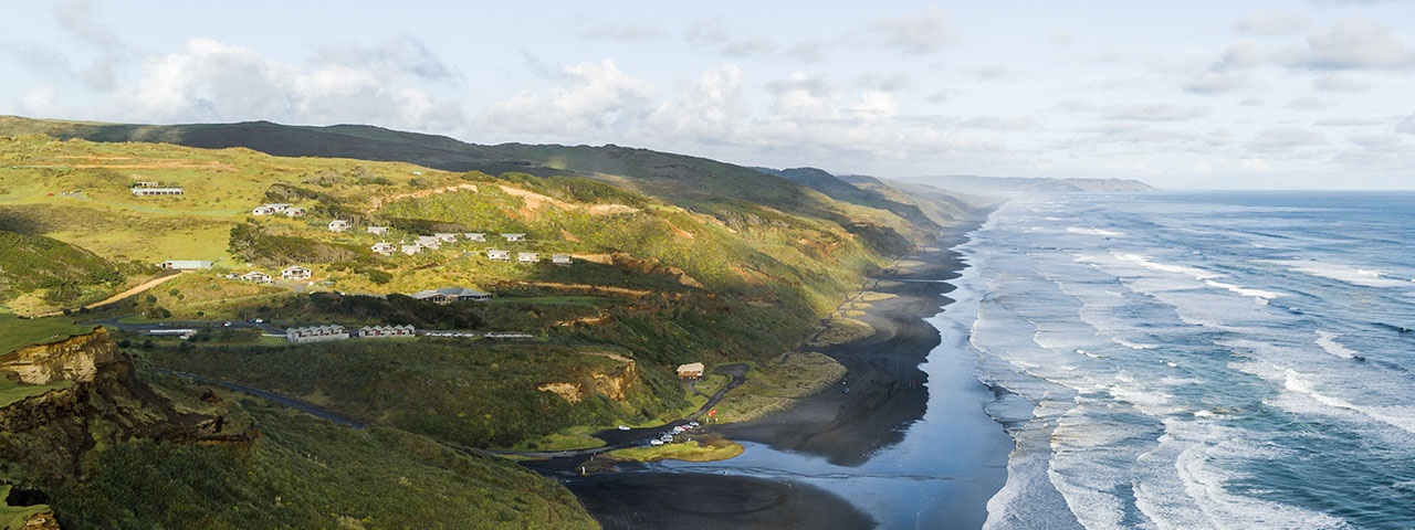 Sweeping black-sand beach and ocean with grassy cliffs