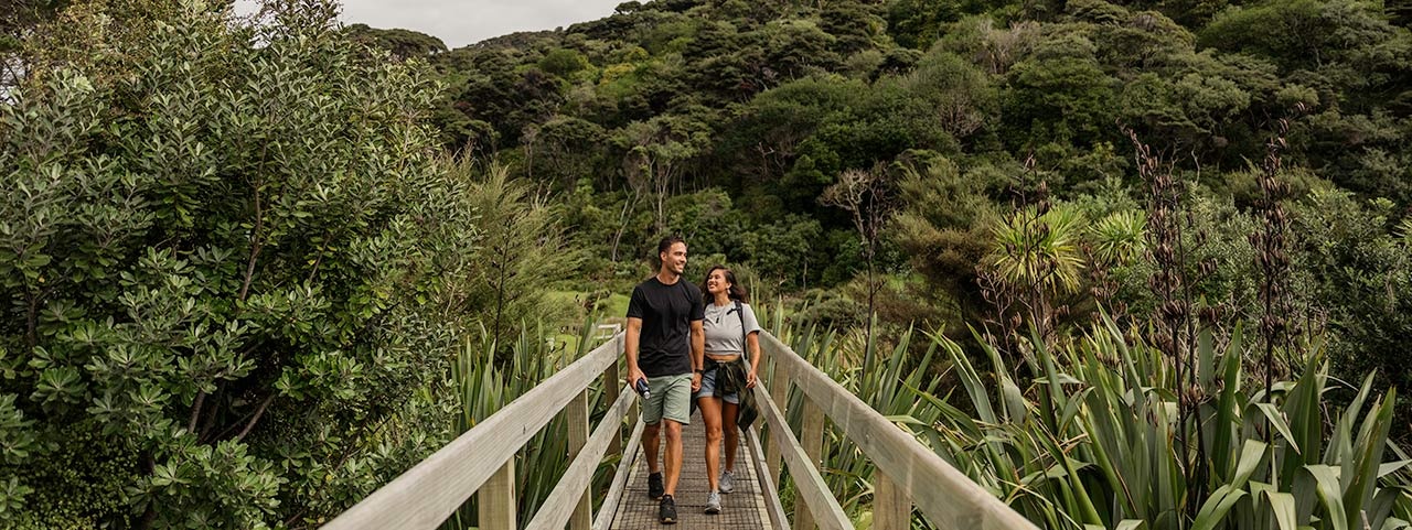 Bethells Te Henga A couple walking on a bridge in native forest at Bethells Te Henga in west Auckland