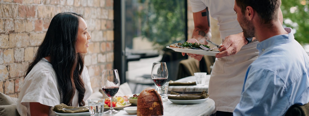 Couple being presented their meal at a restaurant Couple being presented their meal at a restaurant