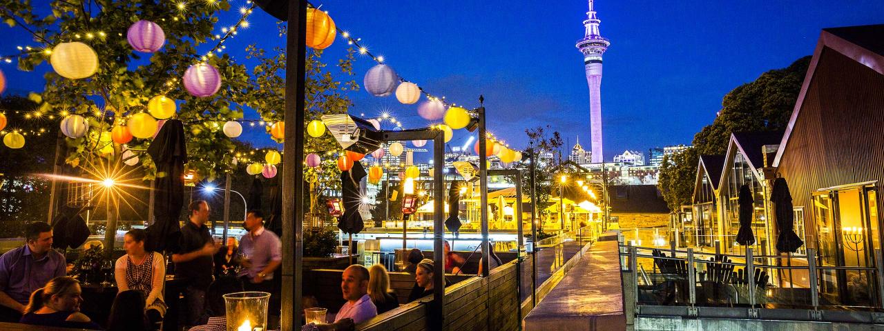 People drinking outdoors at restaurant under coloured lights with Sky Tower in the background (credit: Todd Eyre) 