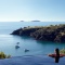 A woman at the edge of an infinity pool looking out to ocean and island views on Waiheke Island