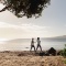 Two women walking along a beach in Auckland with Rangitoto Island in the background
