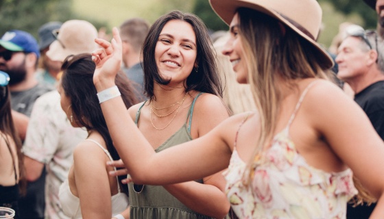 Two women dance in a crowd at a festival
