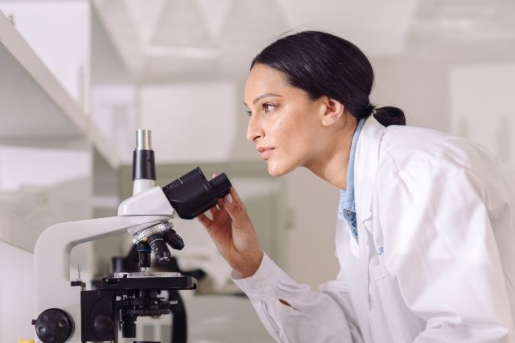 Woman working in research lab looking through microscope