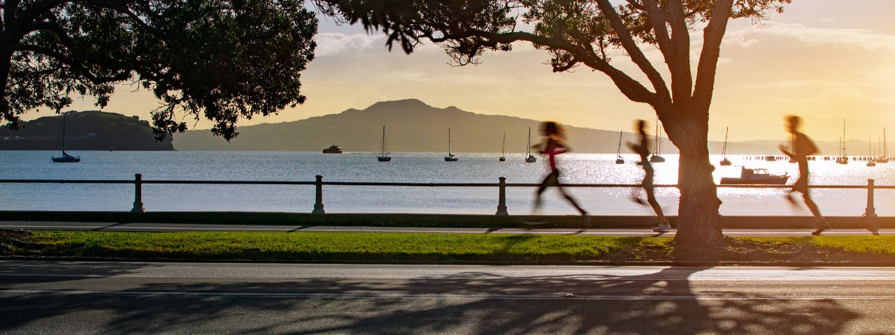 People running along Tamaki Drive with Rangitoto in the background